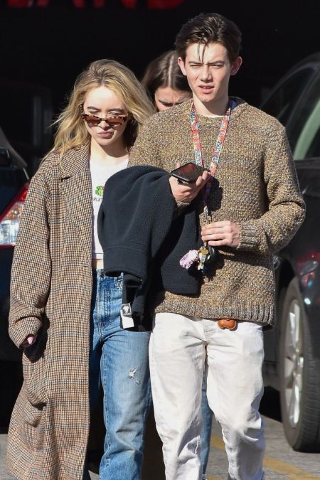 Griffin Gluck in a brown sweater poses for a picture with Sabrina Carpenter.